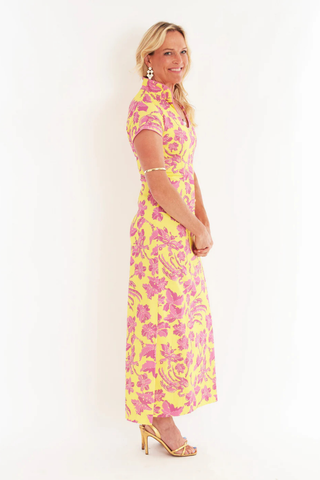 C.K. Bradley Tarpon maxi dress in Lingren Sunset print featuring pink floral motifs on a yellow background, short sleeves, mandarin collar, and side slits