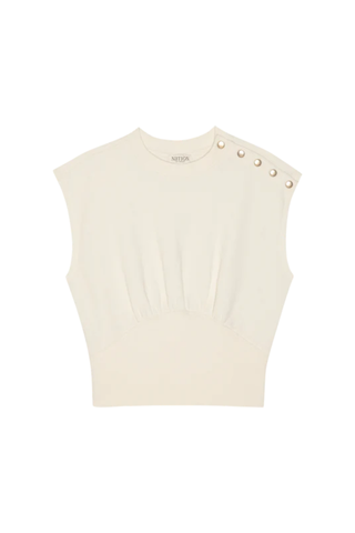 Woman wearing a porcelain white short sleeve sweatshirt with shoulder button detailing from Nation paired with denim.