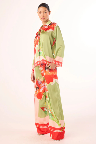 Model wearing the MISA Jaya Top in Scarf Flora Satin featuring a vibrant floral print, satin fabric, button-front closure, long sleeves, and relaxed draped fit paired with coordinating pants