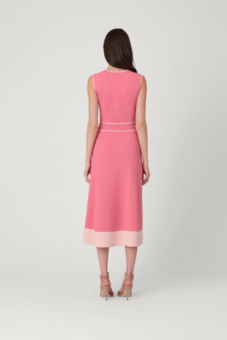 Woman wearing a pink dress with a white belt on a light gray background