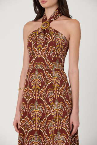 Model wearing the Shoshanna Lainey Dress in Bronze Multi featuring a halter neckline, wooden buckle, fitted bodice, and printed A-line midi skirt.