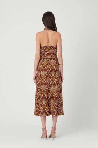Model wearing the Shoshanna Lainey Dress in Bronze Multi featuring a halter neckline, wooden buckle, fitted bodice, and printed A-line midi skirt.