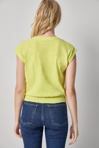 Model wearing the Lilla P Smocked Hem V-Neck Tee in Limeade featuring a soft slub cotton fabric, V-neckline, cap sleeves, and smocked elastic hem paired with dark wash denim jeans