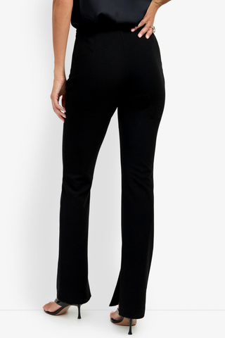 Trina Turk Milena Pant in black featuring a slim-leg silhouette, flat front, side zip closure, and subtle inner hem slits.