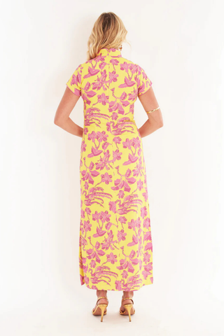 C.K. Bradley Tarpon maxi dress in Lingren Sunset print featuring pink floral motifs on a yellow background, short sleeves, mandarin collar, and side slits