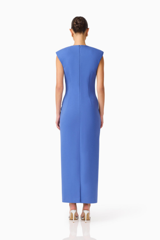 Model wearing the Elliatt Talitha Maxi Dress in Cornflower Blue featuring a plunging V-neckline, structured shoulders, floral appliqué detailing, and a slim column silhouette.