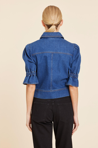 Dolce Cabo Puff Sleeve Shacket in Denim featuring medium wash denim, elbow-length puff sleeves, a pointed collar, zip front, and chest flap pockets.