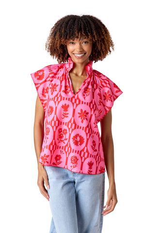 Model wearing Crosby Wilkes Top in Parterre Floral featuring pink and red floral print, flutter sleeves, and a ruffled mock neckline