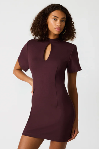 Woman wearing a burgundy dress with a cutout design on a white background