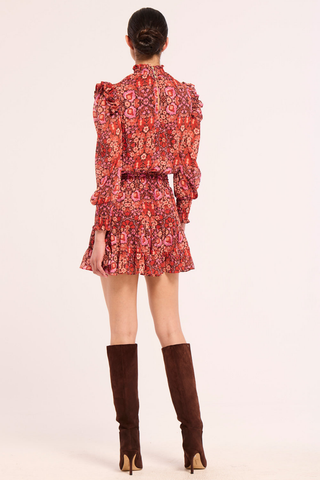 Misa Gianna Dress in Boheme Mix featuring a vibrant red and pink bohemian print, high smocked neckline, long blouson sleeves, and tiered ruffle mini skirt.