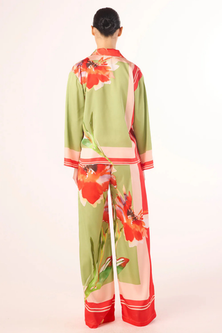 Model wearing the MISA Jaya Top in Scarf Flora Satin featuring a vibrant floral print, satin fabric, button-front closure, long sleeves, and relaxed draped fit paired with coordinating pants