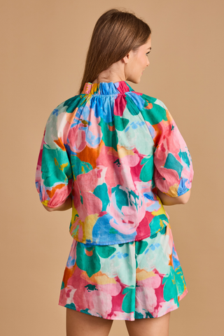 Model wearing the Double A Trish Top in Bougainville featuring a colorful floral print, puff sleeves, gathered ruffle collar, and relaxed silhouette paired with matching shorts