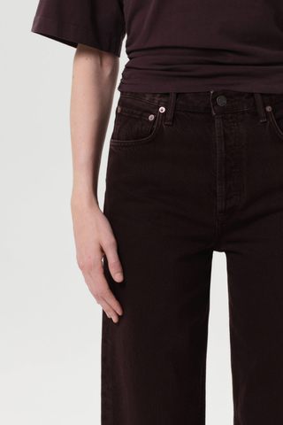 Model wearing the AGOLDE Ren Jean in Sloe Berry featuring a high-rise waist, cropped wide-leg silhouette, and rich dark grape denim with warm brown undertones.