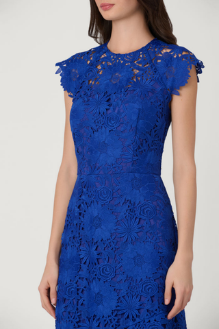 Model wearing the Shoshanna Raven Dress in Cobalt featuring lace fabrication, illusion neckline, scalloped sleeves, and a full-length silhouette.