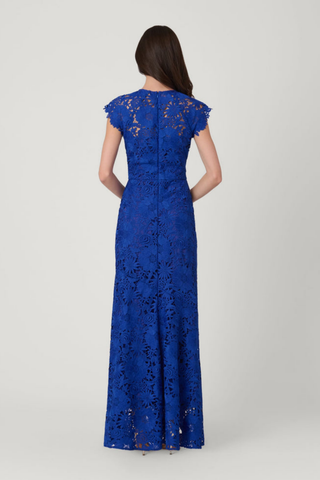 Model wearing the Shoshanna Raven Dress in Cobalt featuring lace fabrication, illusion neckline, scalloped sleeves, and a full-length silhouette.
