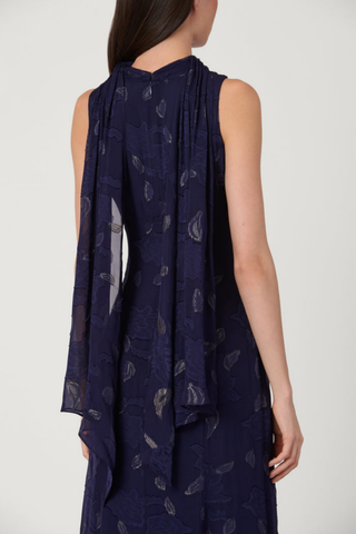 Model wearing the Shoshanna Quinn Dress in Navy/Gold featuring metallic chiffon, a sleeveless high neckline, and flowing full-length skirt.