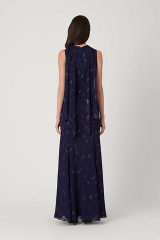 Model wearing the Shoshanna Quinn Dress in Navy/Gold featuring metallic chiffon, a sleeveless high neckline, and flowing full-length skirt.