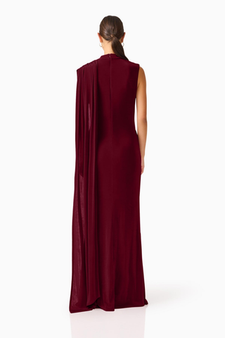 Elliatt Tuloria Sash Gown in Burgundy Red featuring an elegant floor-length silhouette, high neckline, sleeveless design, and dramatic asymmetric draped sash.