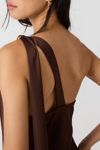 Steve Madden Aurorah Dress in Shaved Chocolate brown featuring a one-shoulder maxi silhouette, gold-tone hardware, and draped back scarf detail.