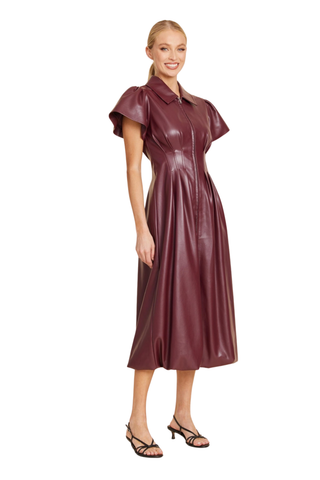 Dolce Cabo Long Maxi Bubble in Burgundy featuring faux leather, flutter sleeves, a pointed collar, structured waist, and long bubble-hem silhouette.