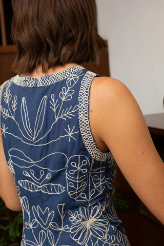 Person wearing a blue sleeveless dress with white floral patterns