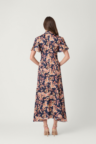 Shoshanna Cinnie Dress in Navy Multi featuring a floral satin print, draped V-neckline, flutter sleeves, gold-tone buttons, and asymmetrical hem.