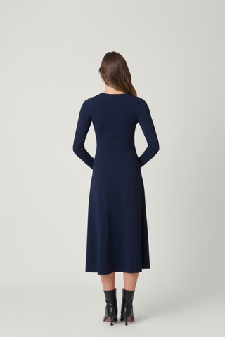 Shoshanna Harrison Dress in Navy featuring a fitted knit bodice, long sleeves, wrap-effect waist, gold buckle detail, and A-line midi skirt.
