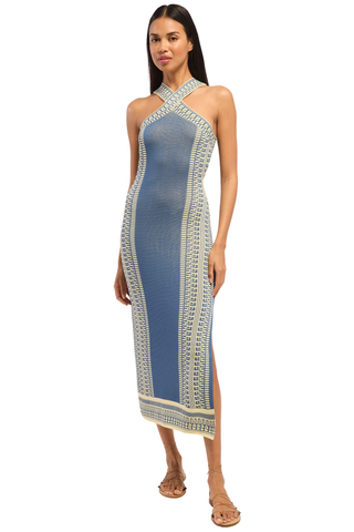Model wearing the Misa Odessa Dress in Aegean Geometry Blue featuring a crossover halter neckline, geometric knit pattern, side slit, and flattering midi silhouette.