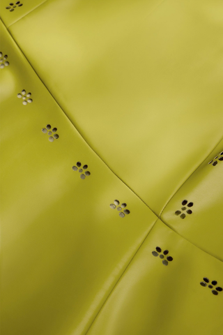 Marie Oliver Casey Skirt in Willow featuring vivid chartreuse vegan leather, laser-cut floral details, and an asymmetrical midi hem.