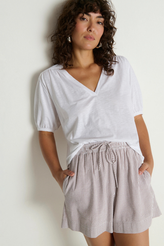 Model wearing the Nation LTD Josie Short in Praline Stripe, a lightweight striped seersucker short featuring an elastic drawstring waist, relaxed fit, side pockets, and a breezy warm-weather silhouette.