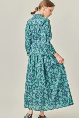 Woman wearing a green floral dress against a plain background