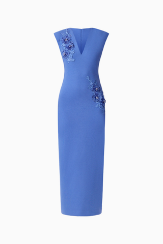 Model wearing the Elliatt Talitha Maxi Dress in Cornflower Blue featuring a plunging V-neckline, structured shoulders, floral appliqué detailing, and a slim column silhouette.