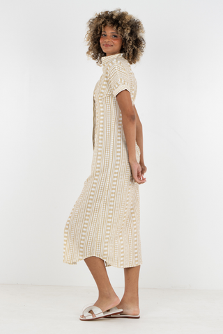 Woman wearing a cream-colored dress with a textured pattern on a white background