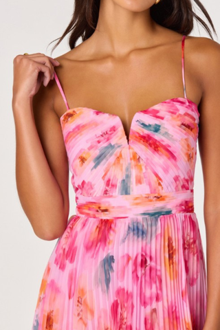Woman wearing a pink multi floral pleated midi dress with spaghetti straps and fitted bodice from ASTR on a white background.