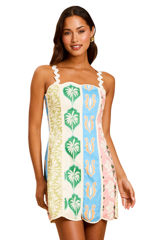 Model wearing Mestiza Sail Away Mini Dress in Beach Bazaar featuring ric rac straps, scalloped neckline, and colorful patchwork-inspired print