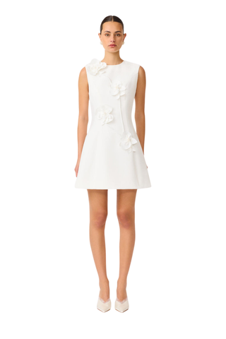 Model wearing the Elliatt Reina Mini Dress in White featuring a sleeveless silhouette, intricate 3D floral appliqué, and a structured A-line mini dress.