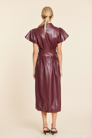 Dolce Cabo Long Maxi Bubble in Burgundy featuring faux leather, flutter sleeves, a pointed collar, structured waist, and long bubble-hem silhouette.