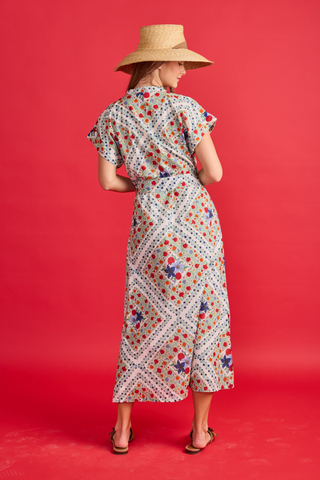Woman wearing a floral dress and wide-brimmed hat on a red background
