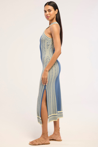 Model wearing the Misa Odessa Dress in Aegean Geometry Blue featuring a crossover halter neckline, geometric knit pattern, side slit, and flattering midi silhouette.