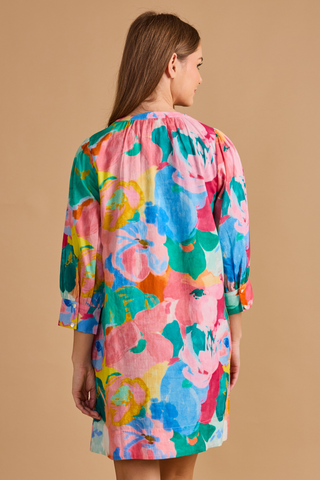 Model wearing the Double A Paloma Dress in Bougainville featuring a colorful watercolor floral print, button-front styling, three-quarter sleeves, and a relaxed mini silhouette