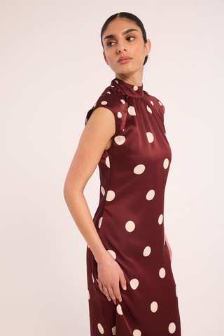 Misa Runi Dress in Polka Dots Mix featuring burgundy satin with oversized cream polka dots, a gathered high neckline, and a contrasting tie-back sash.