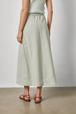 Model wearing the Lilla P Stripe Maxi Skirt in Pool Stripe featuring a soft diagonal stripe pattern, maxi length, flowing A-line silhouette, and lightweight fabric paired with flat sandals