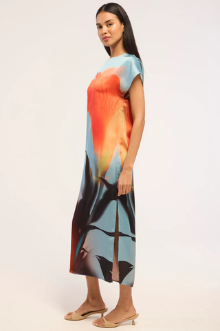 Model wearing the MISA Lenna Dress in Fire Petal featuring a high neckline, cap sleeves, abstract satin print, and elegant midi column silhouette.