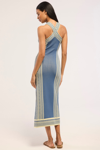Model wearing the Misa Odessa Dress in Aegean Geometry Blue featuring a crossover halter neckline, geometric knit pattern, side slit, and flattering midi silhouette.