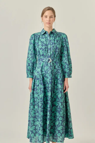 Woman wearing a green floral dress on a plain background