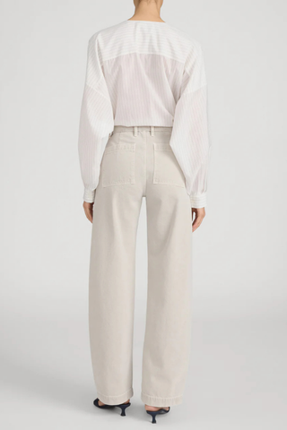 Model wearing FRAME The Bow Cargo in Flax, a high-rise barrel-leg cotton pant with oversized front cargo pockets in a neutral flax wash