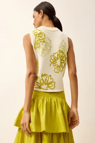 Model wearing the Marie Oliver Natasha Top in Lumino, a cream sleeveless knit sweater featuring oversized yellow floral embroidery, ribbed trim, a crew neckline, and a relaxed cropped fit.