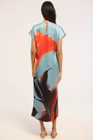 Model wearing the MISA Lenna Dress in Fire Petal featuring a high neckline, cap sleeves, abstract satin print, and elegant midi column silhouette.