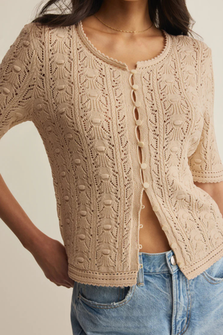 Model wearing Z Supply Adria Pointelle Cardigan in Island Coconut with pointelle knit texture, short sleeves, shell-inspired buttons, and crochet trim details