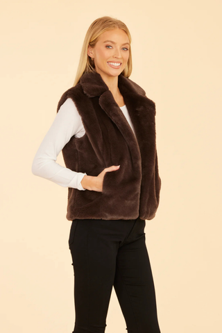 Dolce Cabo Faux Fur Vest in Dark Brown featuring plush chocolate brown faux fur, a notch collar, open front, and side pockets.